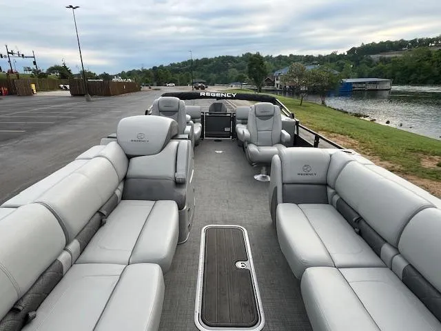 Slide: The Image of 2024 Regency 250LE3 pontoon boat with luxurious seating, docked by a scenic riverside. - 10