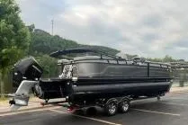 Slide: The Image of 2024 Regency 250LE3 pontoon boat on trailer, parked outdoors. - 2