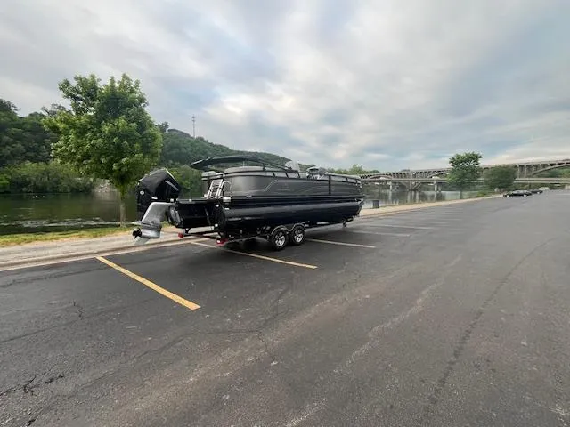 Slide: The Image of 2024 Regency 250LE3 boat on trailer by riverside parking lot. - 5