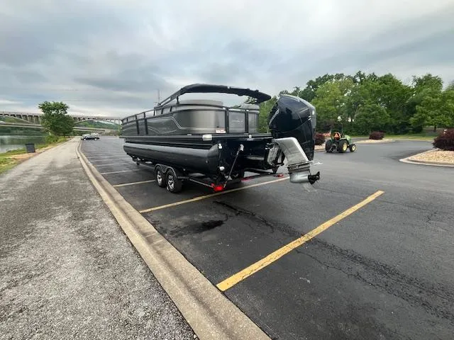 Slide: The Image of 2024 Regency 250LE3 pontoon boat on trailer in parking lot near water. - 6