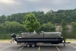 Slide: The Image of 2024 Regency 250LE3 pontoon boat on trailer, parked near a scenic lake. - 8