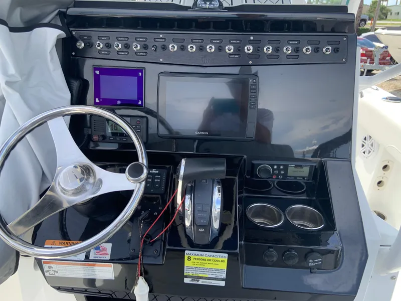 Slide: The Image of 2020 Wellcraft 222F boat dashboard with steering wheel, controls, and navigation screens. - 9