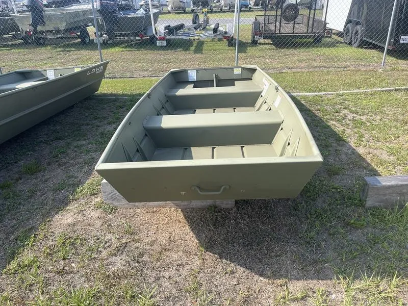 Slide: The Image of 2024 Lowe 1240 boat displayed outdoors on grass near a fence. - 2