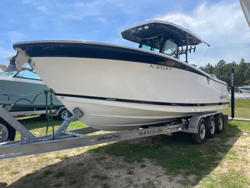 Slide: The Image of 2022 Blackfin 272 CC boat on a trailer, displayed outdoors under a clear sky. - 4