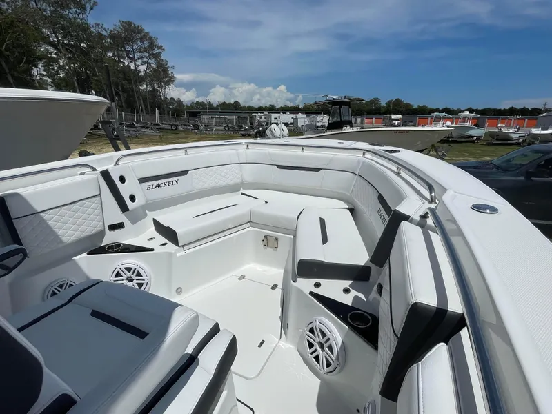 Slide: The Image of 2022 Blackfin 272 CC boat interior with white seating and speakers, docked outdoors. - 8