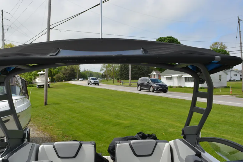 Slide: The Image of 2021 Yamaha Boats 252SD interior view with canopy, parked near a road. - 19