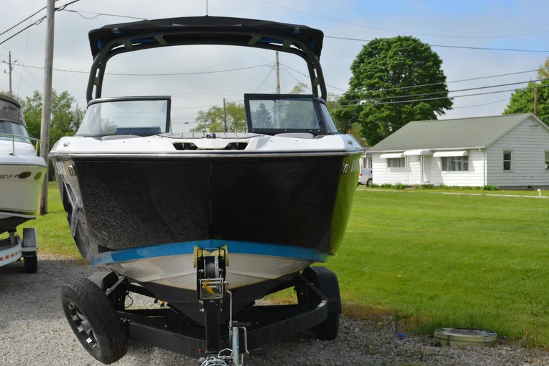 Slide: The Image of 2021 Yamaha Boats 252SD on trailer, parked on gravel, with green lawn and house in background. - 5
