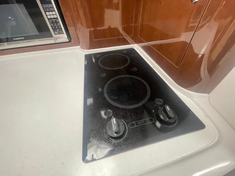 Slide: The Image of Stovetop in 2014 Four Winns Vista 375 yacht kitchen with microwave and wooden cabinetry. - 20