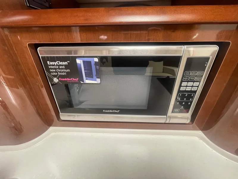 Slide: The Image of Microwave in 2014 Four Winns Vista 375 boat interior, featuring wood paneling and stainless steel finish. - 21