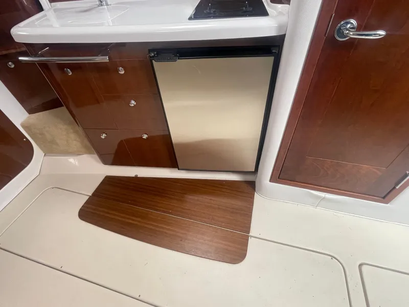 Slide: The Image of 2014 Four Winns Vista 375 interior kitchen with wood cabinetry and compact fridge. - 22