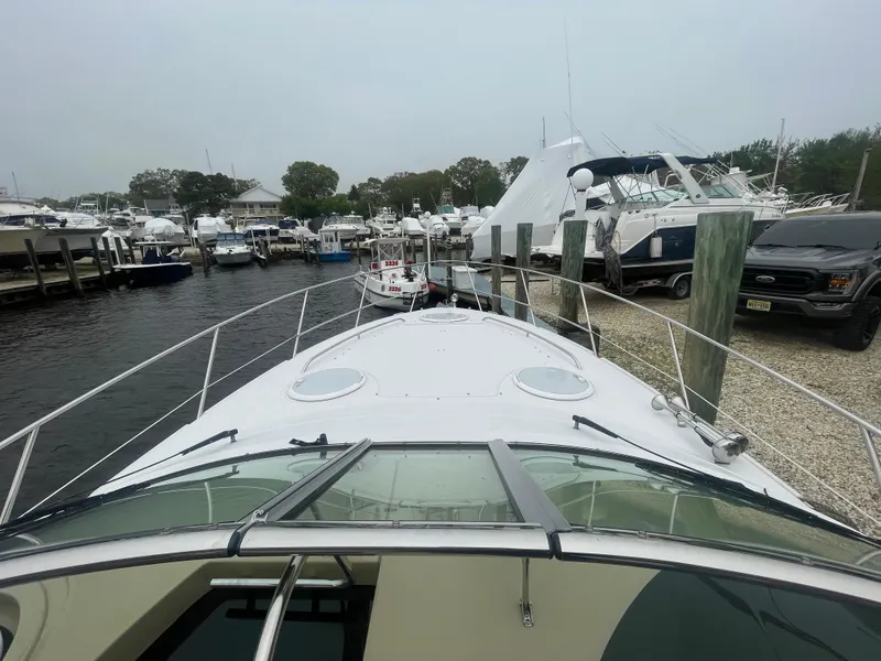 Slide: The Image of 2014 Four Winns Vista 375 docked at a marina, surrounded by boats and vehicles. - 32