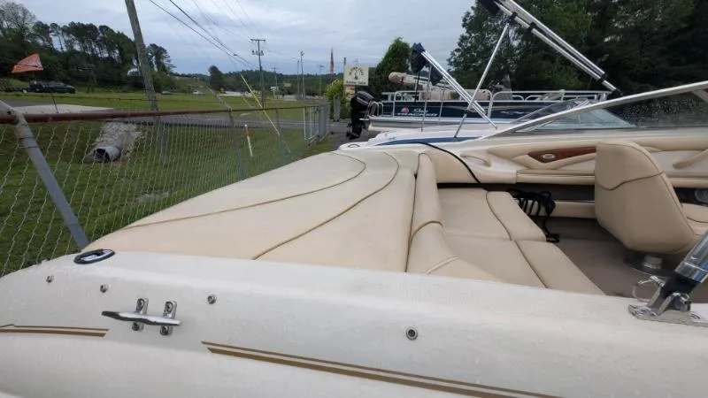 Slide: The Image of 2001 Sea Ray 185 Sport Boat with beige interior, parked near a fence. - 8