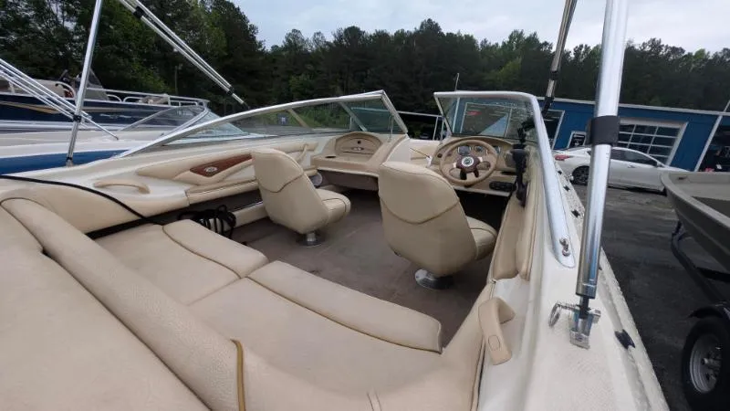 Slide: The Image of 2001 Sea Ray 185 Sport Boat interior with beige seating and steering wheel, parked outdoors. - 9