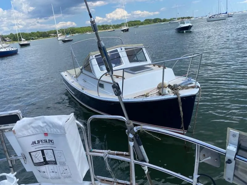 Slide: The Image of 1985 SISU Softtop Cruiser anchored in a scenic harbor with other boats. - 21