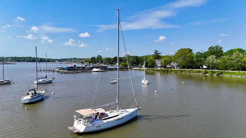 Slide: The Image of 2018 Jeanneau Sun Odyssey 419 sailboat anchored in a serene harbor with clear skies. - 3