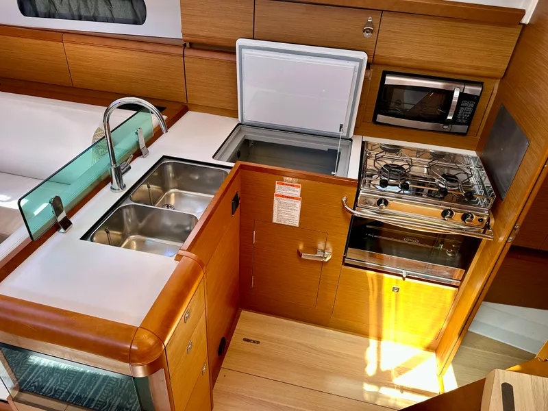 Slide: The Image of 2018 Jeanneau Sun Odyssey 419 yacht kitchen with sink, stove, fridge, and microwave. - 34