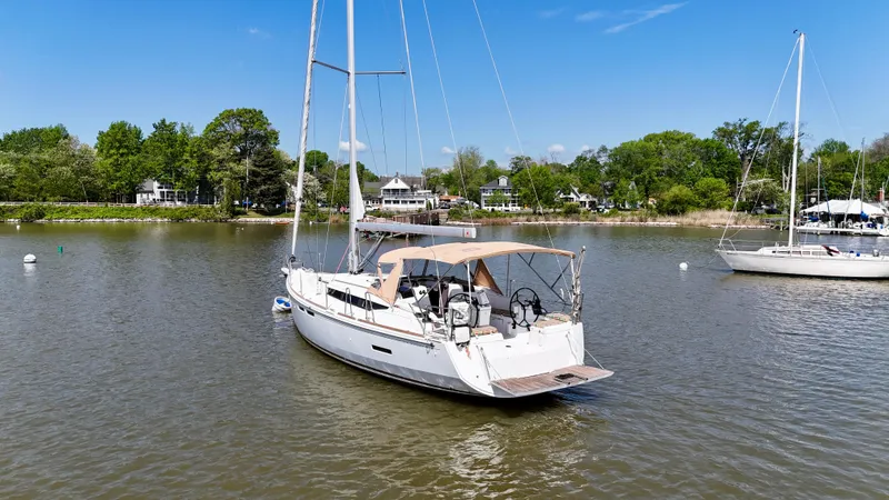 Slide: The Image of 2018 Jeanneau Sun Odyssey 419 sailboat on calm water, surrounded by lush greenery. - 4