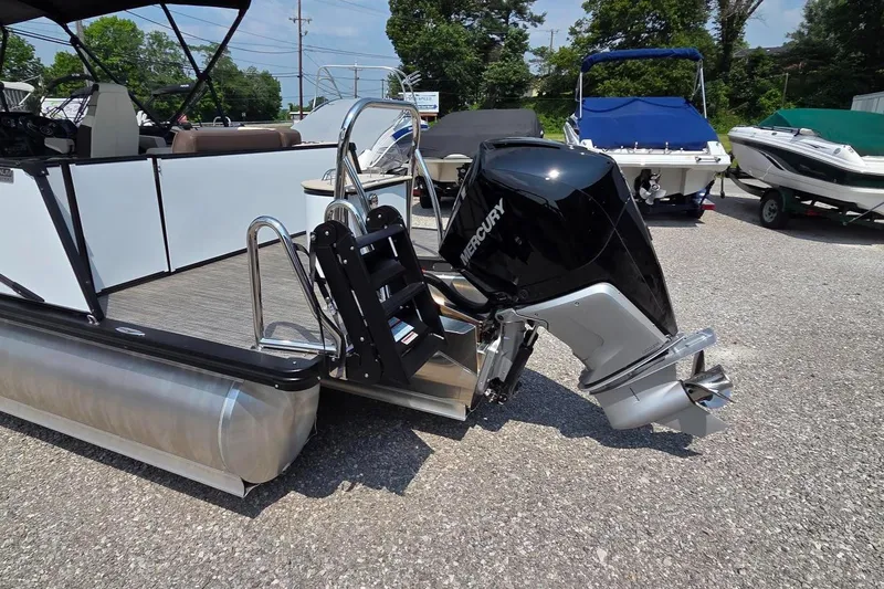 Slide: The Image of 2025 Avalon Platinum Catalina 2385 Elite pontoon boat with Mercury outboard motor, parked on gravel. - 12