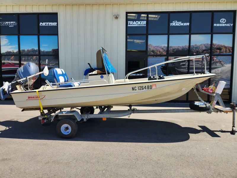 Slide: The Image of 1985 Boston Whaler 15 boat on trailer, parked outside a dealership. - 0