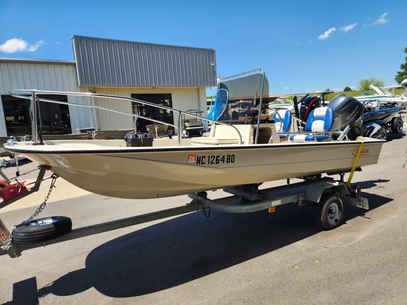 Slide: The Image of 1985 Boston Whaler 15 boat on trailer, parked outdoors under clear blue sky. - 4