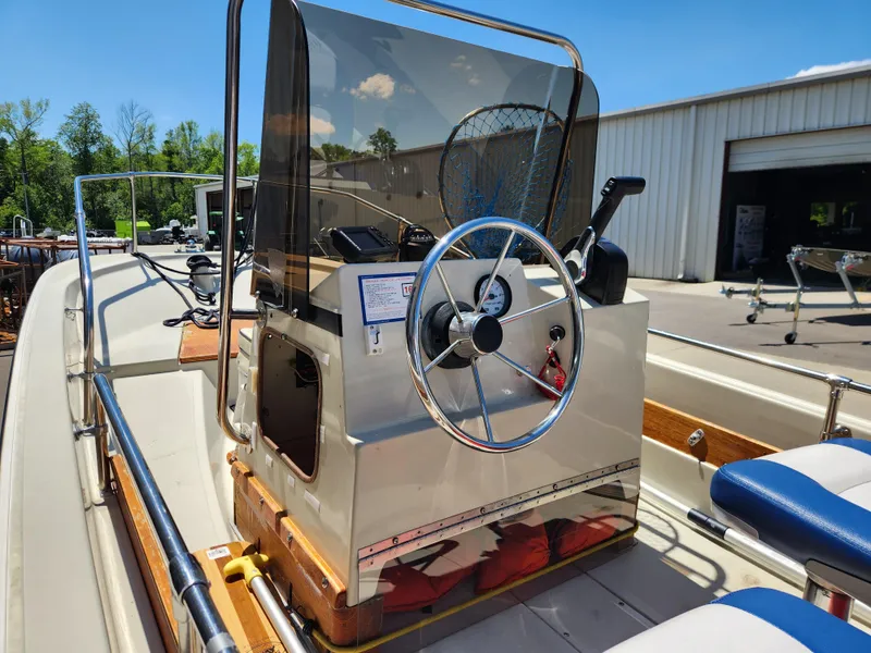 Slide: The Image of 1985 Boston Whaler 15 boat with steering wheel and console, parked outdoors. - 8