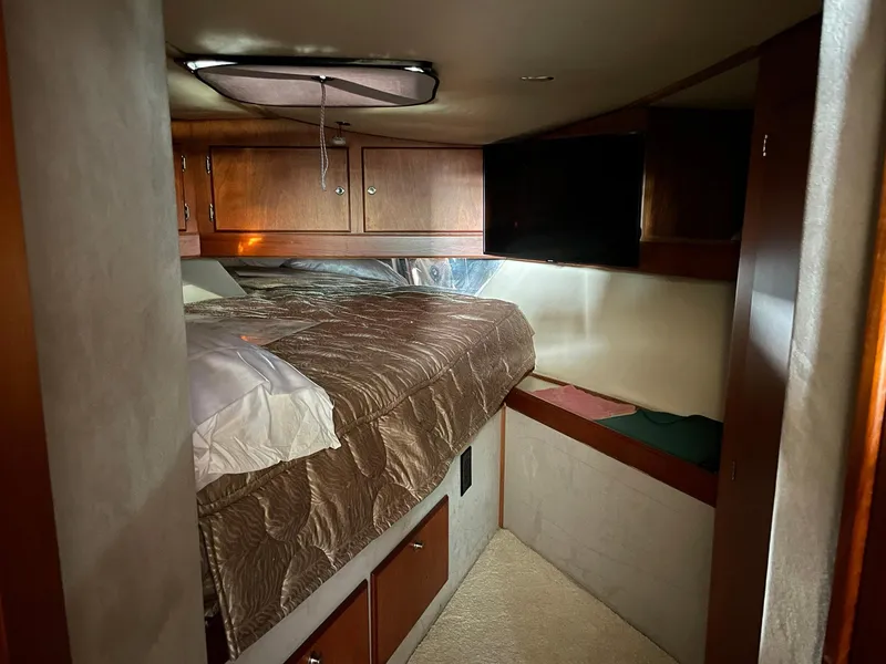 Slide: The Image of 1986 Egg Harbor 41 Convertible cabin interior with bed, wooden cabinets, and cozy lighting. - 10