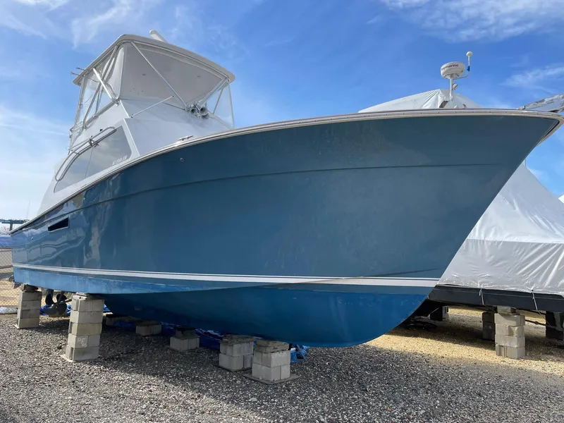 Slide: The Image of 1986 Egg Harbor 41 Convertible boat on blocks, blue hull, clear sky background. - 3