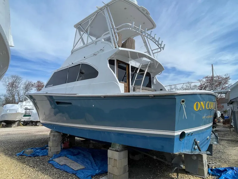 Slide: The Image of 1986 Egg Harbor 41 Convertible boat on blocks, blue hull, white superstructure, outdoor setting. - 38