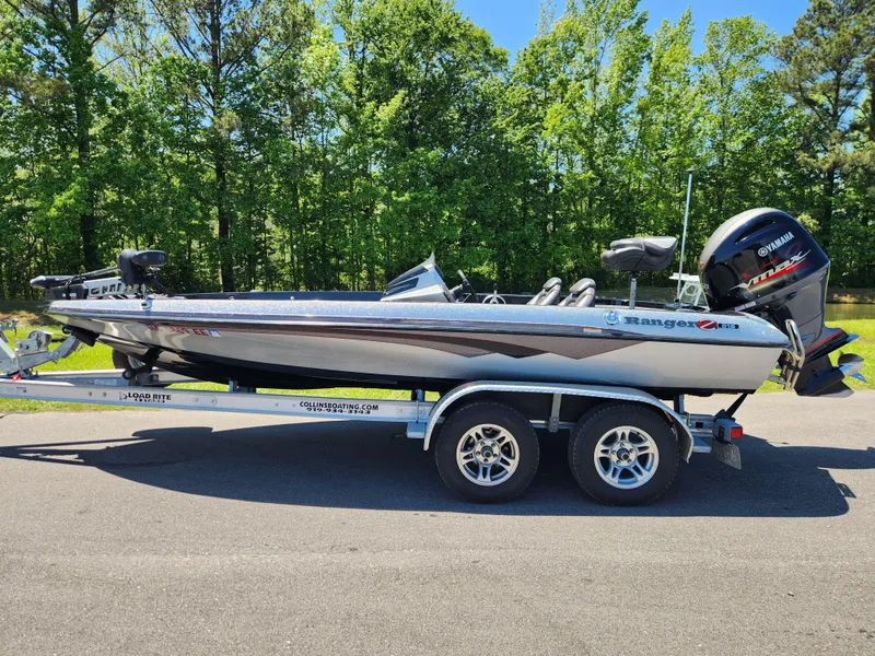 Slide: The Image of 2017 Ranger Z518 boat on trailer, parked outdoors with lush green trees in the background. - 0