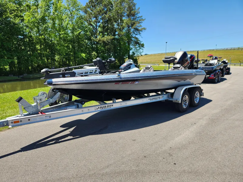 Slide: The Image of 2017 Ranger Z518 boat on trailer, parked near a lake with trees in the background. - 1