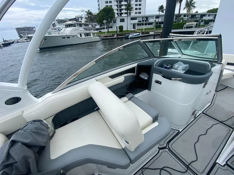 Slide: The Image of 2021 Cobalt 25SC boat interior with white seating, docked near waterfront buildings. - 14