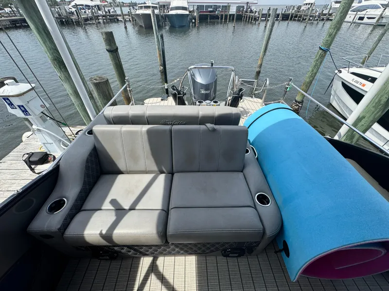 Slide: The Image of 2021 Barletta L25UE pontoon boat with gray seating and blue mat, docked at marina. - 11