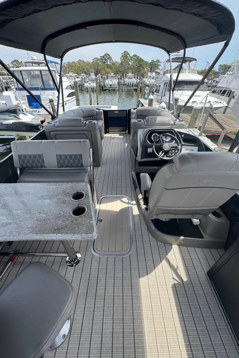 Slide: The Image of 2021 Barletta L25UE pontoon boat interior with seating, table, and steering wheel. - 12