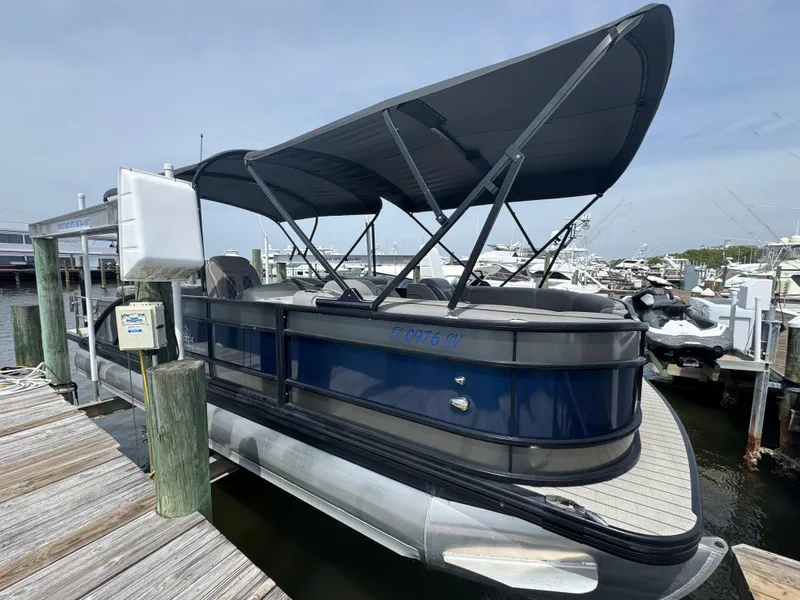 Slide: The Image of 2021 Barletta L25UE pontoon boat docked with canopy, blue and gray design. - 2