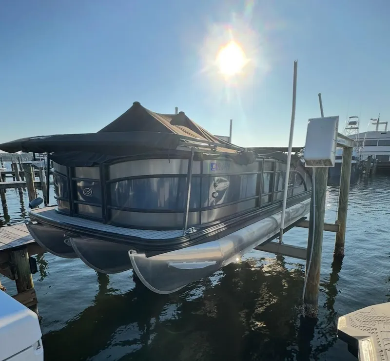 Slide: The Image of 2021 Barletta L25UE pontoon boat docked under bright sun. - 3
