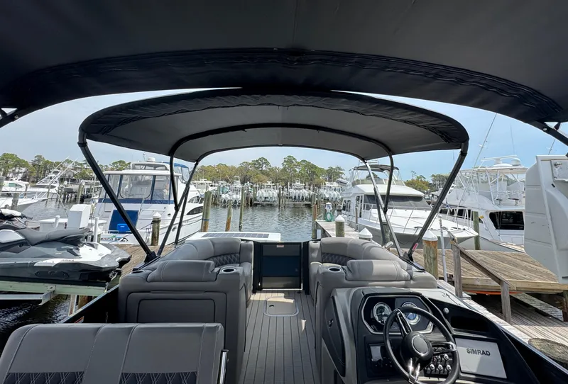 Slide: The Image of 2021 Barletta L25UE pontoon boat interior at marina, featuring helm and seating. - 6