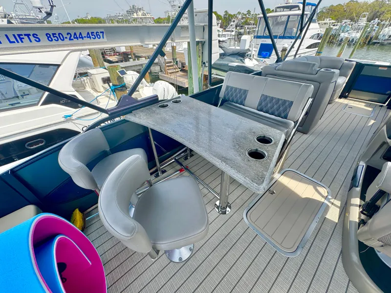 Slide: The Image of 2021 Barletta L25UE pontoon boat interior with seating and table, docked at marina. - 7