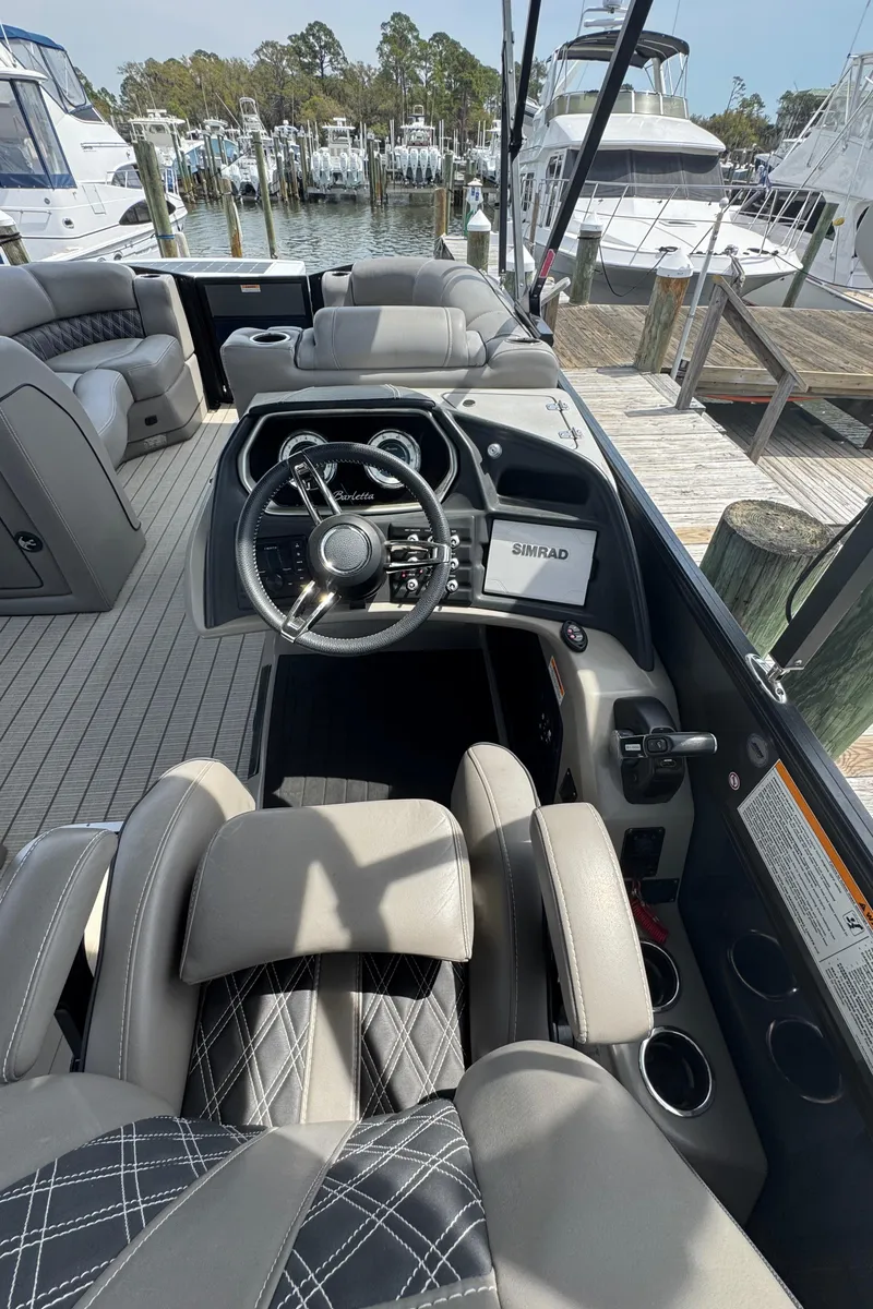 Slide: The Image of 2021 Barletta L25UE boat interior with steering wheel and seating at a marina. - 9