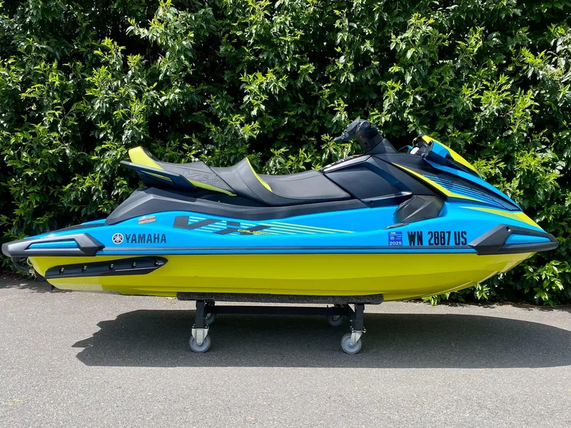 Slide: The Image of 2023 Yamaha VX Cruiser with Audio, blue and yellow, parked on pavement, lush green background. - 1