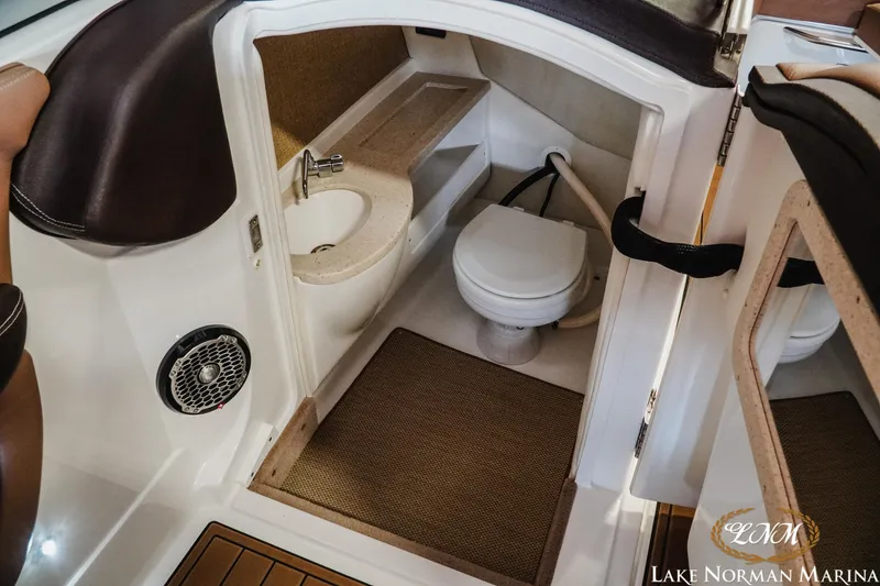 Slide: The Image of 2013 Cobalt A28 boat interior with compact bathroom, featuring a toilet and sink. - 17