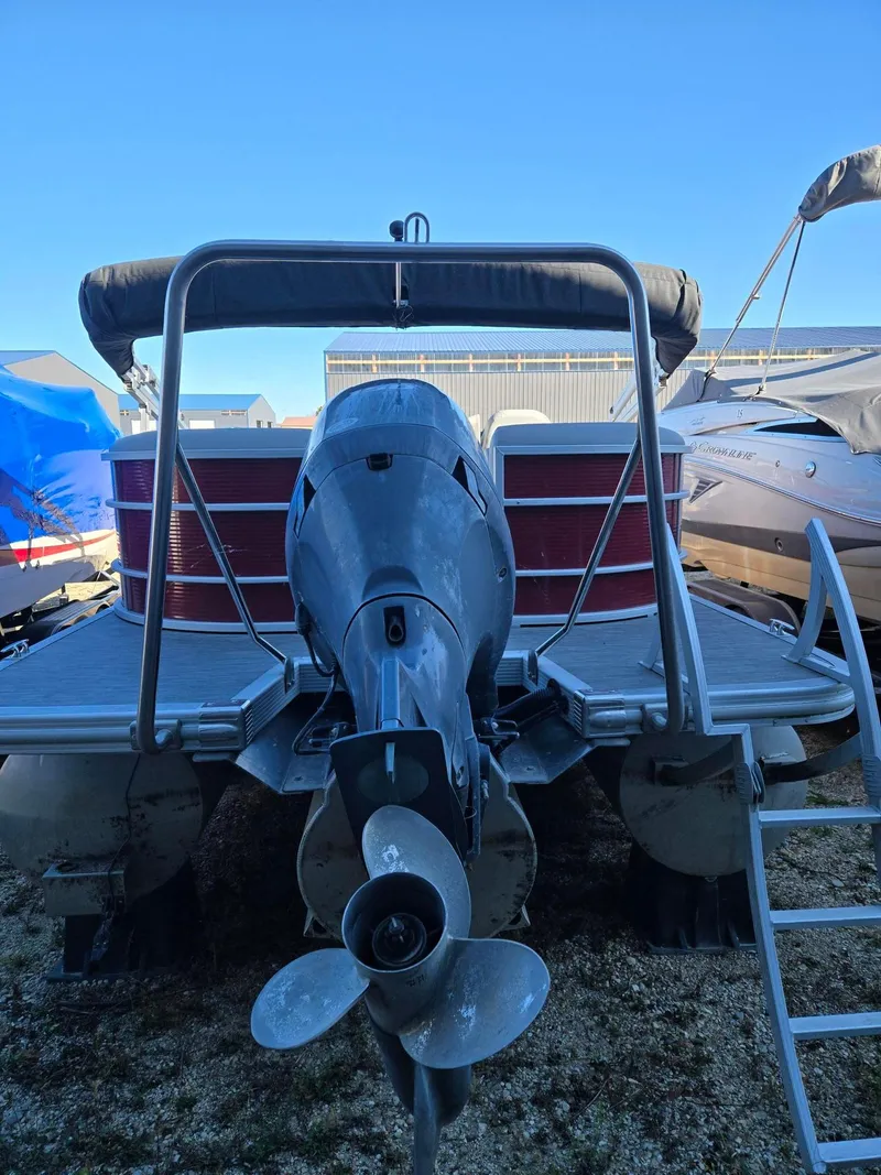Slide: The Image of 2023 Bennington 22SXSRC pontoon boat with outboard motor, docked on gravel. - 3