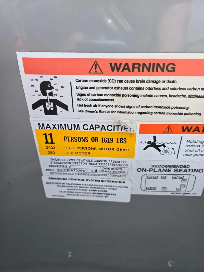 Slide: The Image of Warning label on 2021 Lowe Retreat 230 High Performance boat, showing maximum capacity and safety instructions. - 23