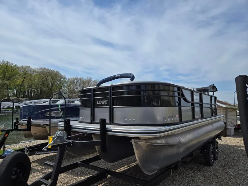 Slide: The Image of 2021 Lowe Retreat 230 High Performance pontoon boat on trailer by the water. - 4