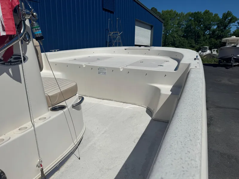 Slide: The Image of 2014 Carolina Skiff 218 DLV boat deck with seating, docked near blue building. - 5