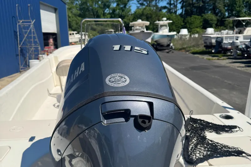 Slide: The Image of 2014 Carolina Skiff 218 DLV with Yamaha 115 engine in a boatyard setting. - 7
