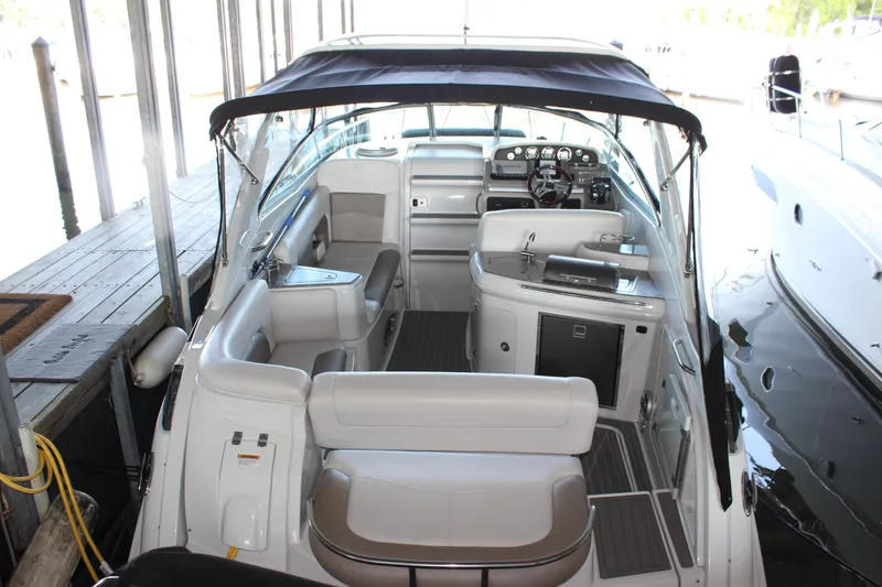 Slide: The Image of 2021 Crownline 294 CR boat interior with seating, helm, and canopy in a marina setting. - 0