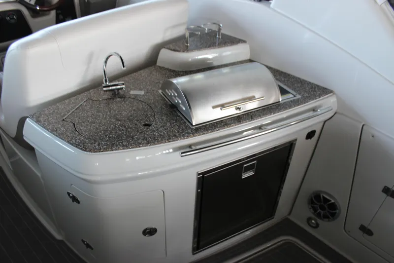 Slide: The Image of 2021 Crownline 294 CR boat interior with kitchenette, featuring sink, grill, and storage. - 15