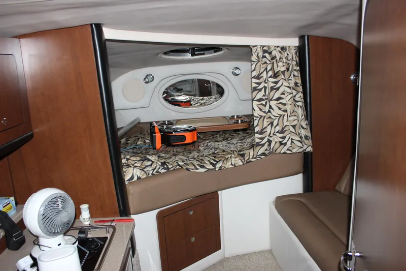 Slide: The Image of 2021 Crownline 294 CR cabin interior with bed, fan, and kitchenette. - 24