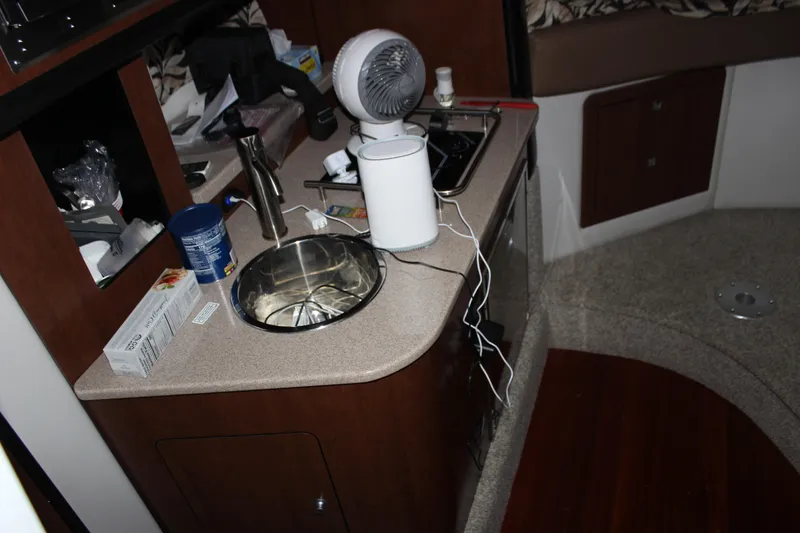 Slide: The Image of 2021 Crownline 294 CR boat interior kitchen with sink, fan, and countertop appliances. - 25