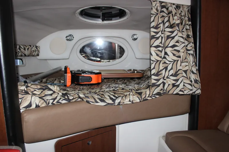 Slide: The Image of 2021 Crownline 294 CR cabin interior with patterned bedding and porthole window. - 26